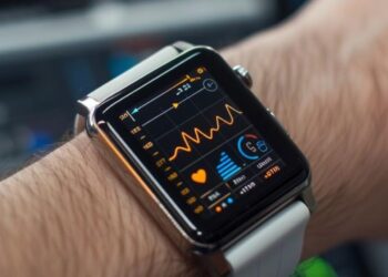 This image captures the convenience of modern technology with a close-up shot of a sophisticated smartwatch worn on a wrist. The smartwatch screen brightly displays a health tracking interface, indicating a focus on fitness and wellbeing. The wearer likely values staying informed about their physical health, with metrics such as heart rate prominently shown. The blurred background suggests a busy lifestyle, possibly within an urban environment, where such gadgets are indispensable tools for managing life's daily demands.